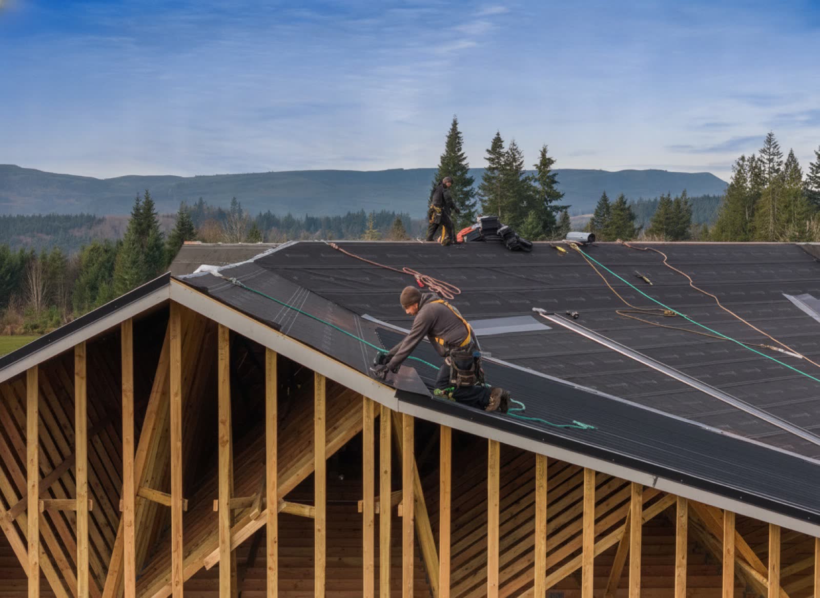 Roofer inspecting a moss-covered aging asphalt shingle roof on a 1940s craftsman bungalow in Longview Washington with overcast PNW sky